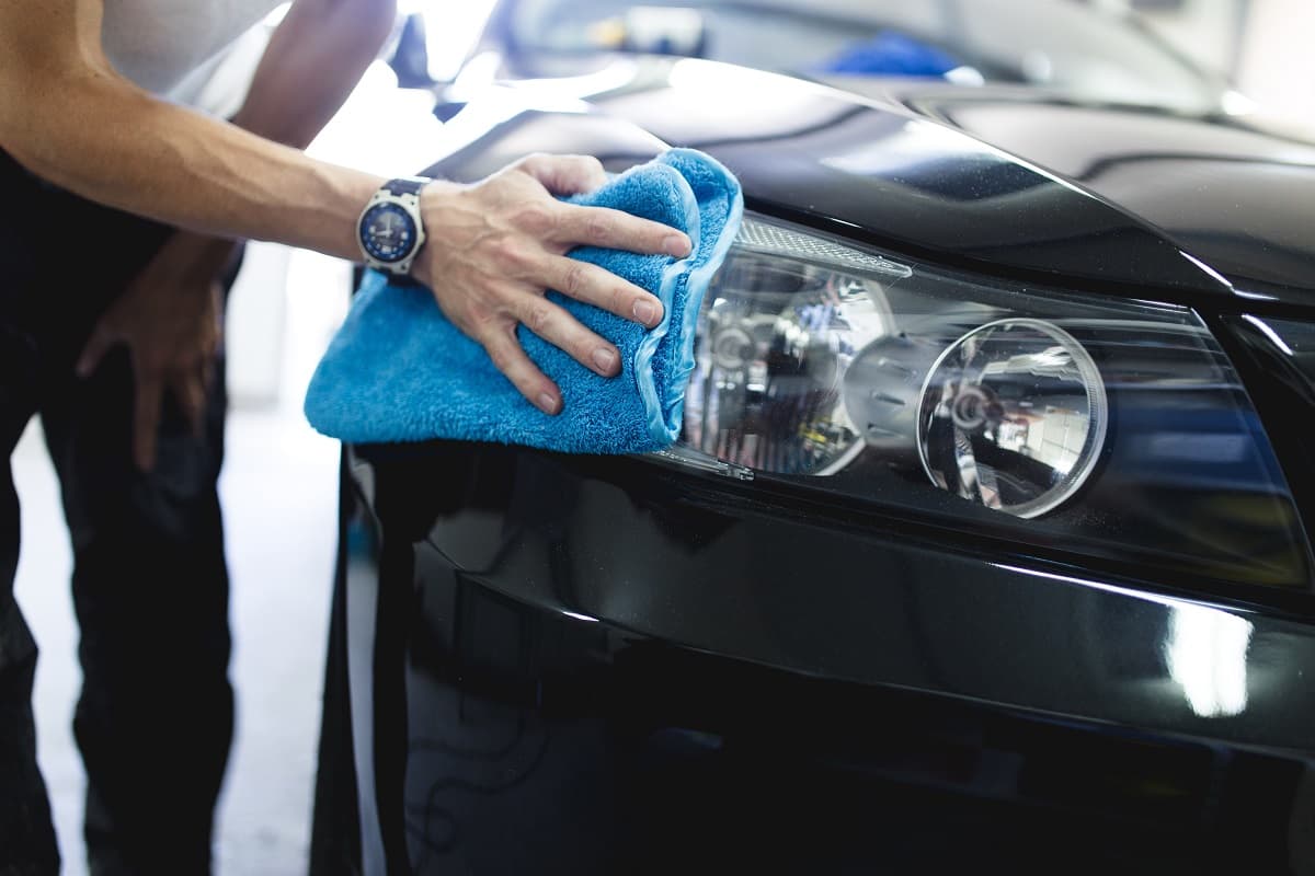 Technician cleaning a car headlight with a microfiber cloth